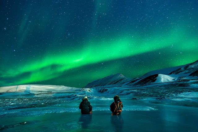 Viewing Northern Lights in the Alaska wilderness.  You can see the silhouette of mountains in the dark background.