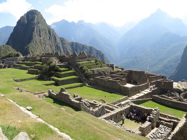 Macchu Picchu, ancient ruins along a hill with beautiful mountains in the background